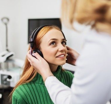 Patient trying on a modern discreet hearing aid during a professional fitting