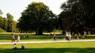 Families and friends relaxing, walking, and biking in a sunlit park, the kind of community gathering better hearing helps you enjoy fully