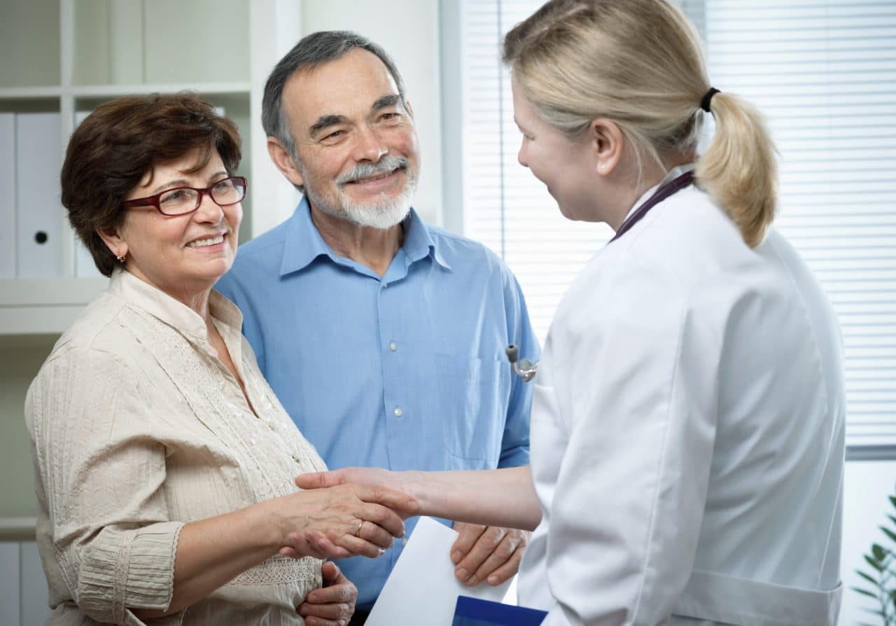 Hearing care professional greeting an older couple at a consultation