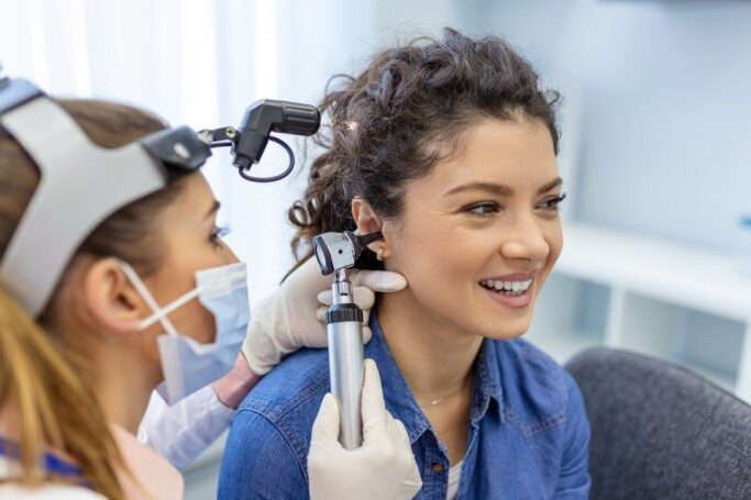 Hearing specialist examining a patient's ear with an otoscope during a hearing screening